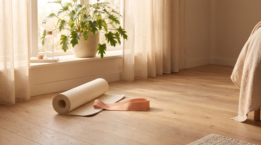 Tapete de yoga enrollado y banda elástica junto a una ventana